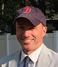 A man wearing a red sox hat and smiling.