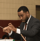 A man in a suit and tie holding a conductor 's baton.